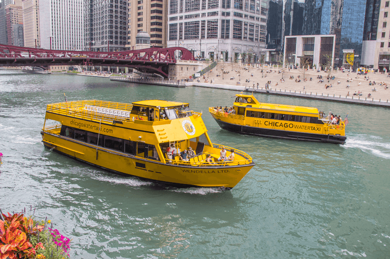 A Chicago Water Taxi cruising the traffic-free river while cars cross the bridge above