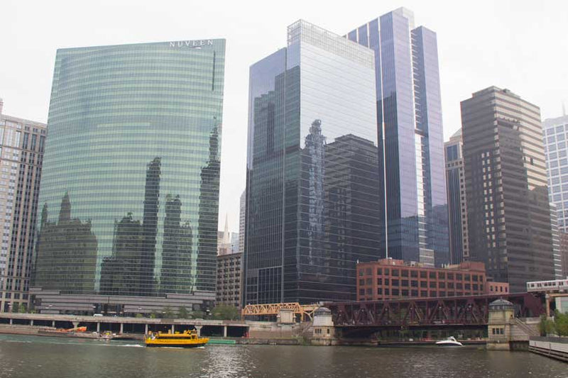 A yellow Chicago Water Taxi boat navigating the Chicago River through downtown