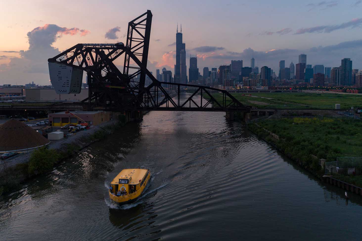 A Chicago Water Taxi boat with a covered lower deck moving along the Chicago River on an overcast day