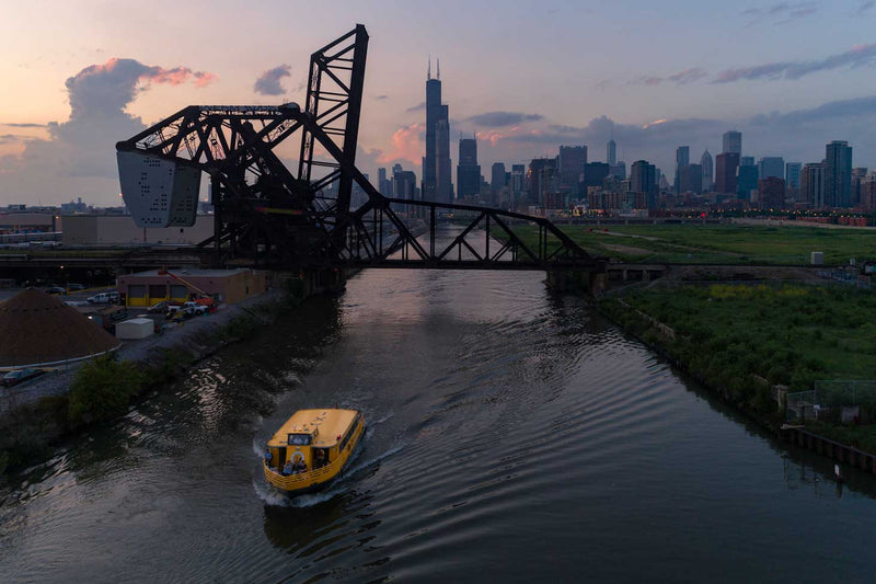 A Chicago Water Taxi boat with a covered lower deck moving along the Chicago River on an overcast day