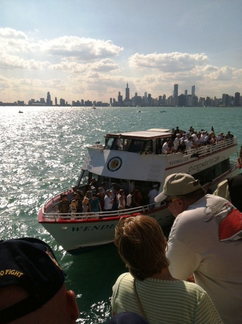 A Wendella boat full of passengers on Lake Michigan with the distant Chicago city skyline on the horizon.